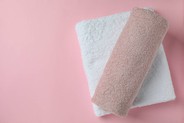 Clean folded towels on pink background, space for text - Foto, imagen