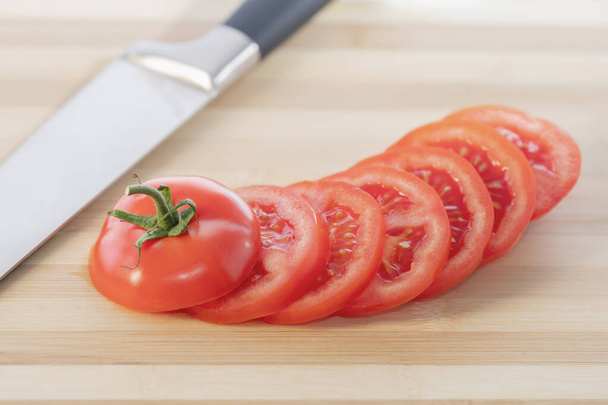 Świeżo krojony pomidor izolowany na drewnianej desce do krojenia: selektywne skupienie. Koncepcja zdrowej żywności - Zdjęcie, obraz