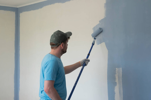 Worker painting walls with a roller during flat renovation - Foto, immagini