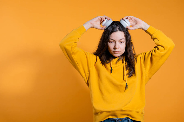 Music lovers enjoy music. A young woman in a yellow hoodie with white wireless headphones, - Foto, Imagem