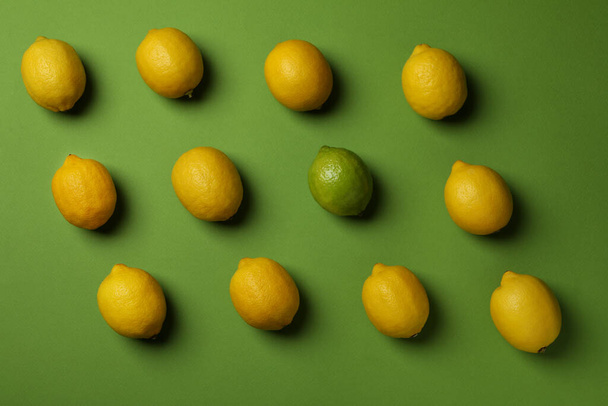 Reife Zitronen und Limetten auf grünem Hintergrund, Draufsicht - Foto, Bild