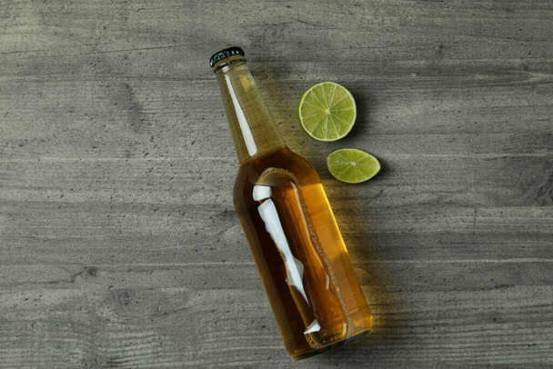 Garrafa de cerveja e limão em fundo cinza texturizado - Foto, Imagem