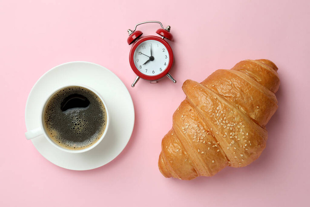 Croissant, coffee and alarm clock on pink background - Foto, Imagen