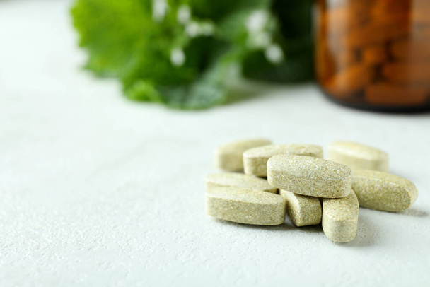 Травяные таблетки на белом текстурированном столе, закрыть - Фото, изображение