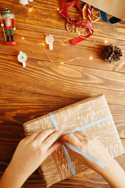 Frauenhände binden Schleife an Weihnachtsgeschenk. - Foto, Bild