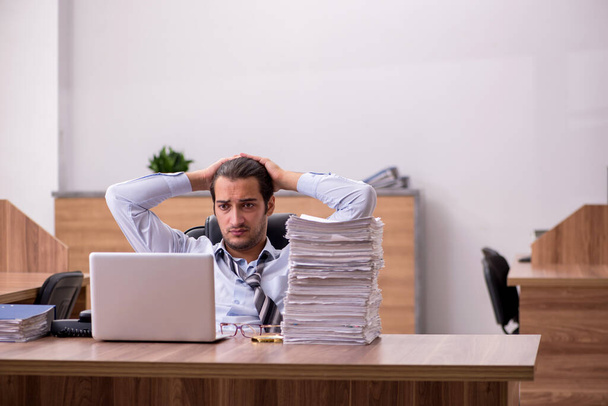 Młody mężczyzna pracownik niezadowolony z nadmiernej pracy w biurze - Zdjęcie, obraz