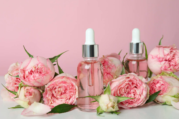 Έννοια φροντίδας του δέρματος με αιθέριο έλαιο τριαντάφυλλο σε ροζ φόντο - Φωτογραφία, εικόνα