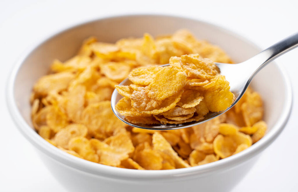 Cornflakes on a spoon. Cornflakes in a bowl in the background. - Photo, Image