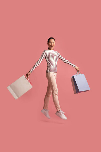 Koncepcja sezonowej sprzedaży. Radosny młody Azji kobieta skoki z kolorowe torby na zakupy - Zdjęcie, obraz