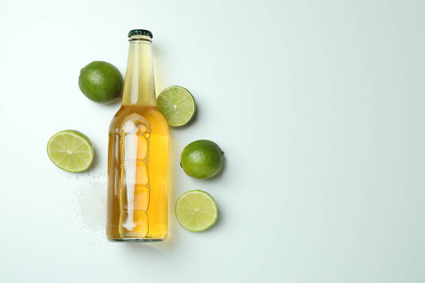 Fles bier, limoenen en zout op witte ondergrond - Foto, afbeelding