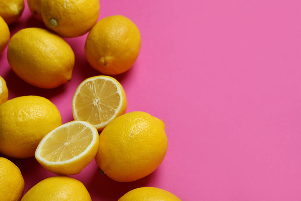 Ripe lemons on pink background, space for text - Фото, изображение