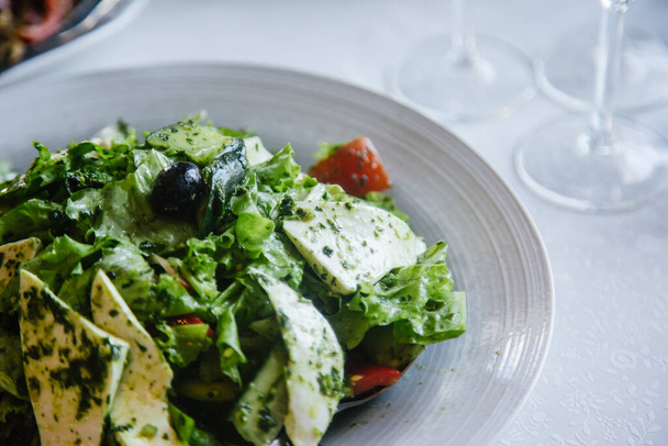 Caesar salaatti yrttejä, juustoa ja oliiveja valkoisella lautasella. Terveellinen syöminen - Valokuva, kuva