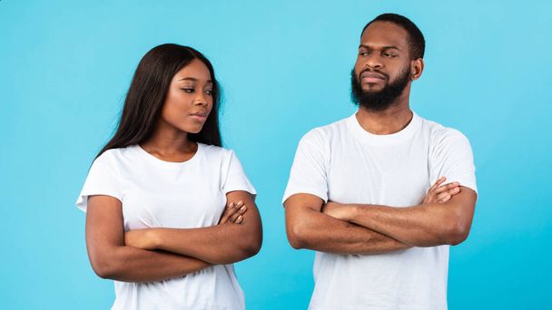Offended black couple standing with crossed arms, blue studio wall - Φωτογραφία, εικόνα