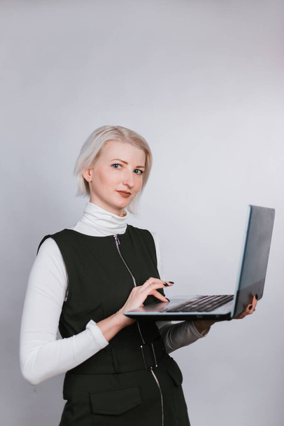Kluge Frau mit Laptop in der Hand tippt Text auf die Tastatur. Blond auf weißem Hintergrund - Foto, Bild
