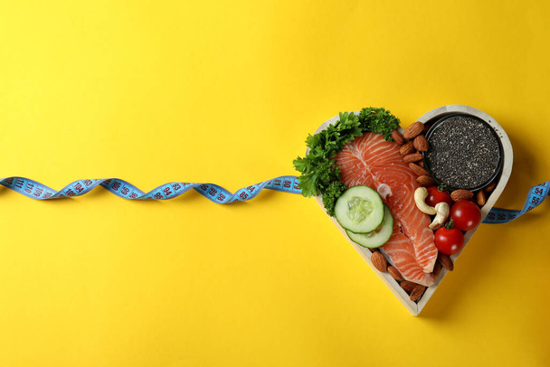 Zdravé jídlo v srdci a měřicí páska na žlutém pozadí - Fotografie, Obrázek