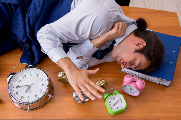Jonge mannelijke werknemer slapen in het kantoor in time management co - Foto, afbeelding