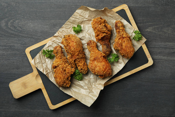 Concept of tasty eating with fried chicken on dark wooden background - Фото, изображение
