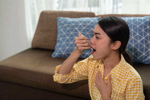 Portrait of young Asian woman using an asthma inhaler - Photo, Image