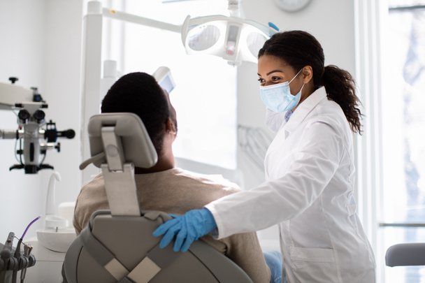 Egy fekete fogorvos nő és egy férfi páciens portréja a fogászati klinikán. - Fotó, kép