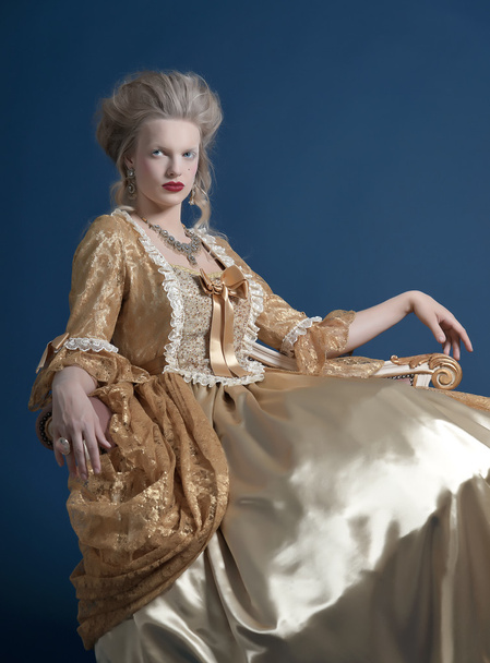 Retro baroque fashion woman wearing gold dress. Sitting on vinta - Fotoğraf, Görsel