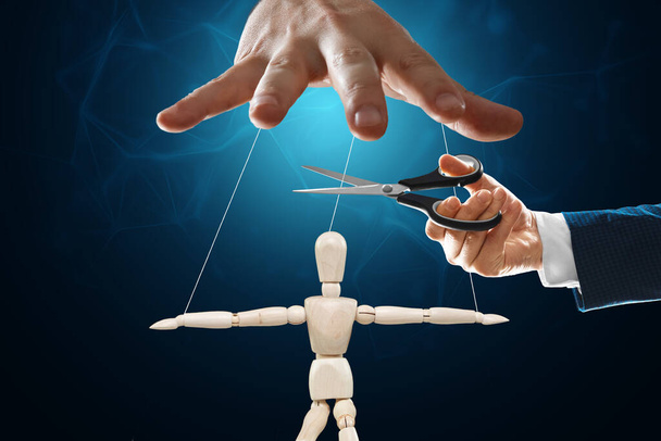 A man's hand cuts the threads between the puppeteer and the puppet with scissors. The concept of liberation from slavery, freedom, shadow government, world conspiracy, manipulation, control - Foto, immagini