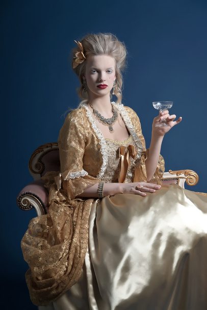 Retro baroque fashion woman wearing gold dress. Holding wine gla - Photo, Image