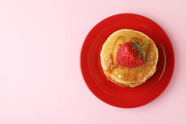 Plate with pancakes with strawberry and caramel on pink background - Photo, Image