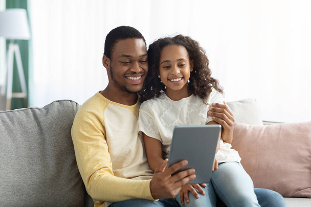 Ευτυχισμένος μαύρος μπαμπάς και κόρη χρησιμοποιώντας ψηφιακή ταμπλέτα μαζί - Φωτογραφία, εικόνα