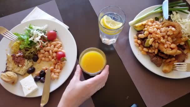 Im Zeitraffer essen Menschen mit Messern und Gabeln von vollen Tellern und trinken Säfte - Filmmaterial, Video