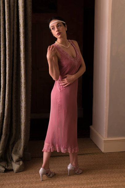 Pink 1920s flapper dress worn by an elegant young woman - Фото, изображение