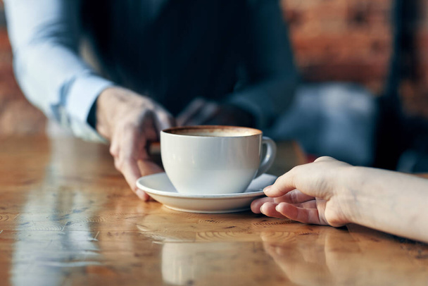 gelukkige barman serveert een kopje koffie aan een patiënt in een cafe drank baksteen muur interieur - Foto, afbeelding
