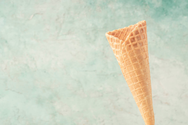 close-up de um cone de sorvete vazio sobre fundo verde com espaço de cópia - Foto, Imagem