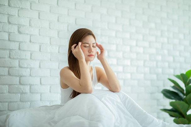 Asian young Woman has a Migraine and headache after wake up in cozy bedroom at home,Suddenly of painful attack on head massage around on pain spot,Healthcare Concept - Foto, imagen