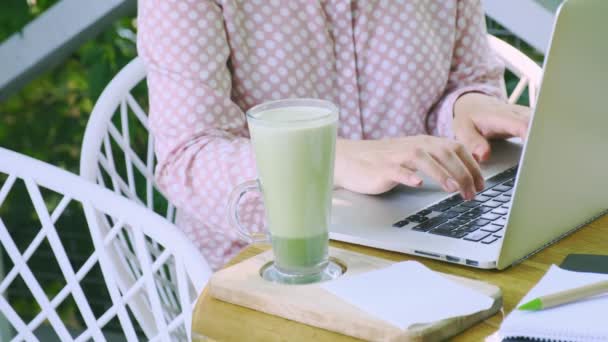 Glass Cup of Green Matcha late Coffee or Tea stay near Workplace of Freelancer or Blogger. Concept of Healthy Food in Menopause Period. - Footage, Video