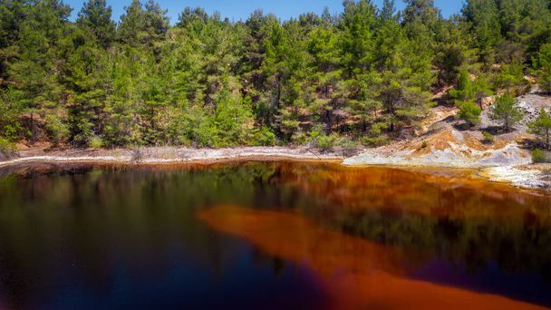 放棄されたオープンピット鉱山で有毒な赤い湖の海岸。その色は酸と重金属の高いレベルに由来します。 - 写真・画像
