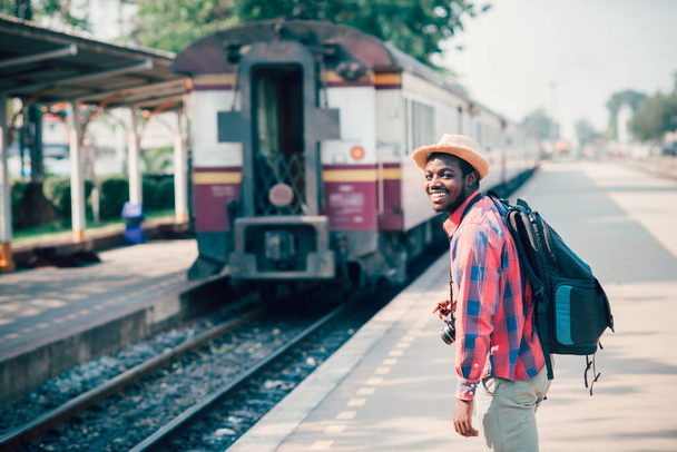 Hombre africano viajero caminando y esperando el tren en la estación de tren. Concepto de viaje aventura. - Foto, Imagen