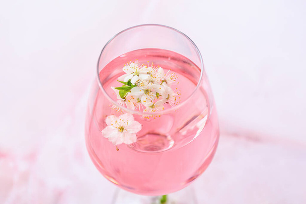 Glass with tasty drink and blooming branches on color background - Fotografie, Obrázek
