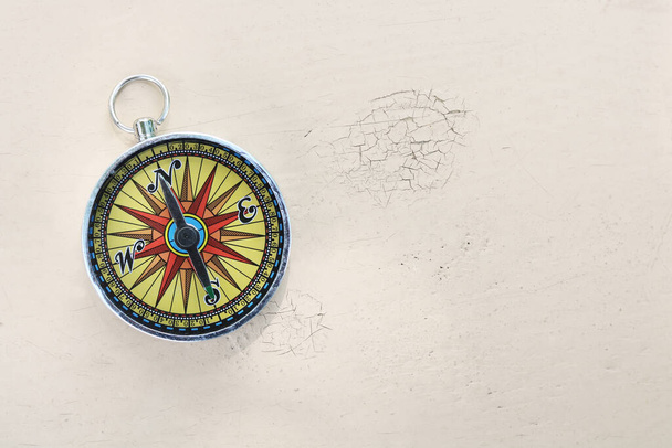 Старый классический навигационный компас на желтом винтажном фоне с царапинами и трещинами в краске как символ туризма с компасом, путешествия с компасом и активного отдыха на открытом воздухе с компасом - Фото, изображение