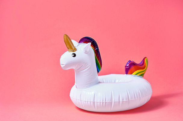Inflatable white unicorn pool toy on pink background. Creative minimal concept. - Фото, изображение