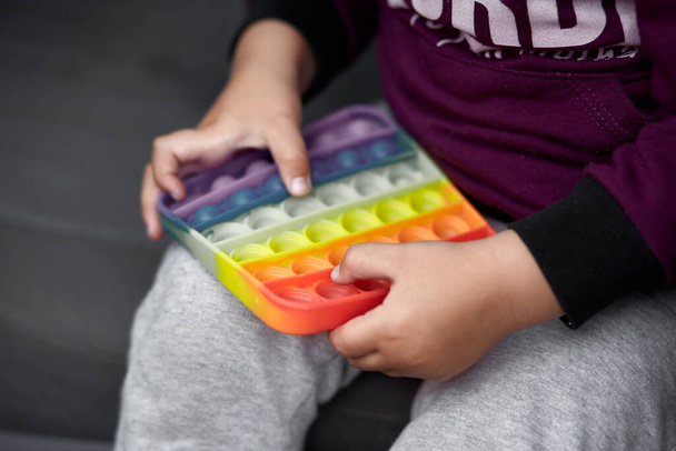 Rainbow sensory fidget. Colorful antistress sensory toy fidget push pop it in kids hands. Antistress trendy pop it toy. New trendy silicone toy. - Photo, Image