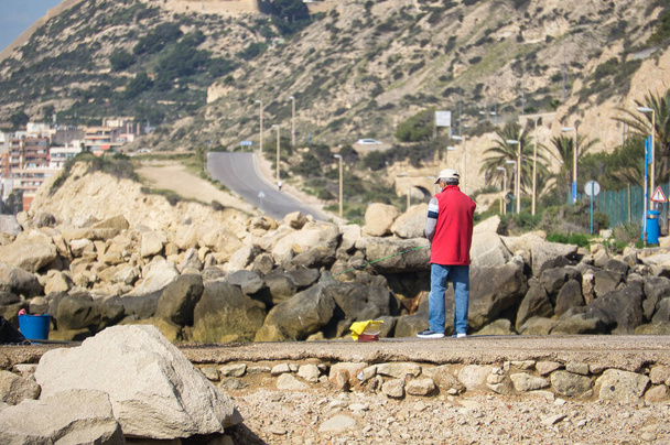 osoba łowiąca ryby na wybrzeżu miasta Alicante, we Wspólnocie Walenckiej, Hiszpania. widok - Zdjęcie, obraz