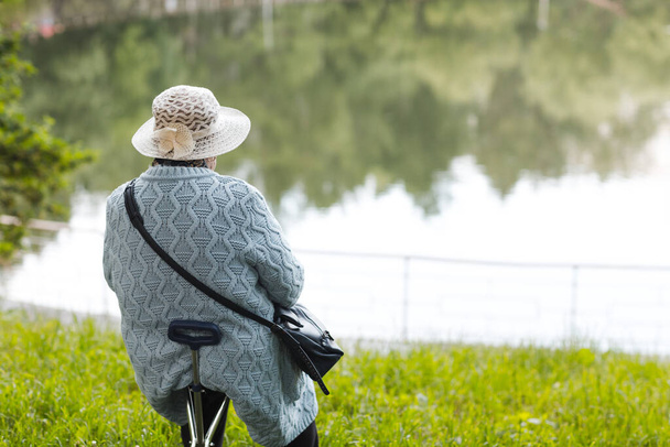 Anciana mujer mayor sentada en verano cerca del estanque del lago. Feliz concepto de vejez. - Foto, imagen