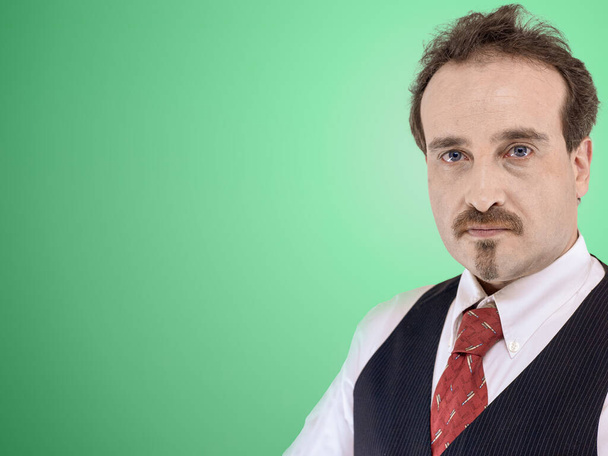 Homem de camisa branca, colete e gravata roupas de negócios olhando para a frente da câmera de um fundo verde claro. Espaço livre no lado esquerdo da imagem - Foto, Imagem