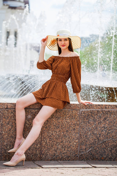 Full-length portrait of a young beautiful girl posing against the backdrop of a city fountain - Foto, Imagen