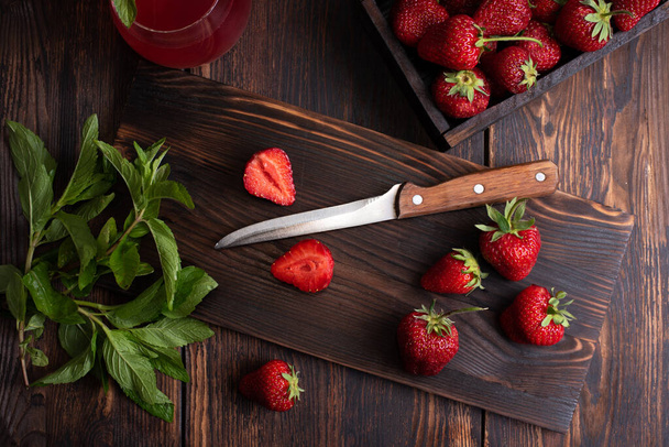 Ζουμερές ώριμες φράουλες σε ένα ξύλο κοπής με μαχαίρι σε ξύλινο φόντο, ρουστίκ στυλ, υγιεινή διατροφή με ωμά τρόφιμα, κοντινό πλάνο. - Φωτογραφία, εικόνα