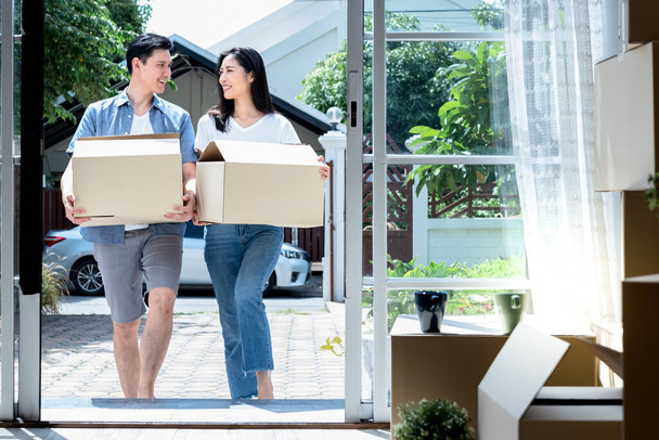 Ázsiai pár, férj és vonzó feleség segítik egymást, hogy felemeljék a dobozt Boldogan, hogy új otthonba költözzenek Házasság és családi élet indításához.. - Fotó, kép