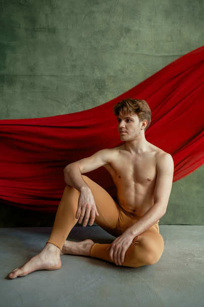 Männerballett, Tanzstudio, Grunge-Wand und rotes Tuch auf dem Hintergrund. Performer mit muskulösem Körper, Anmut und Eleganz der Bewegungen - Foto, Bild
