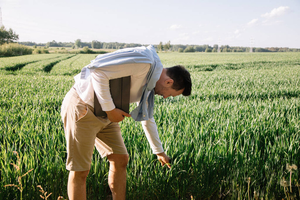 Giovane agricoltore con cartella sotto il braccio 40 anni a controllare il suo raccolto foraggero, concetto di piccola attività economica - Foto, immagini