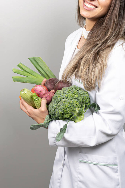 Ofisinde gülümseyen kadın beslenme uzmanı, sağlıklı sebzeler ve meyveler gösteriyor. Sağlık ve diyet konsepti. Yaşam biçimi. - Fotoğraf, Görsel