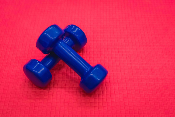 Mancuernas azules fitness equipo de peso en el fondo del suelo rojo del gimnasio. - Foto, imagen